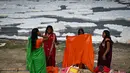 Sejumlah wanita membersihkan diri seusai mandi di sungai Yamuna sebagai bagian dari ritual untuk festival Chhath Puja yang akan datang di New Delhi, Senin (8/11/2021). Sungai yang sangat dianggap suci oleh umat Hindu India ini dipenuhi lapisan busa karena limbah beracun. (Sajjad HUSSAIN / AFP)