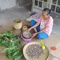 Nyang Nok (58) sedang meracik ramuan tradisonal di depan teras rumahnya di Desa Jambi Kecil, Kabupaten Muaro Jambi. (Liputan6.com / Gresi Plasmanto)