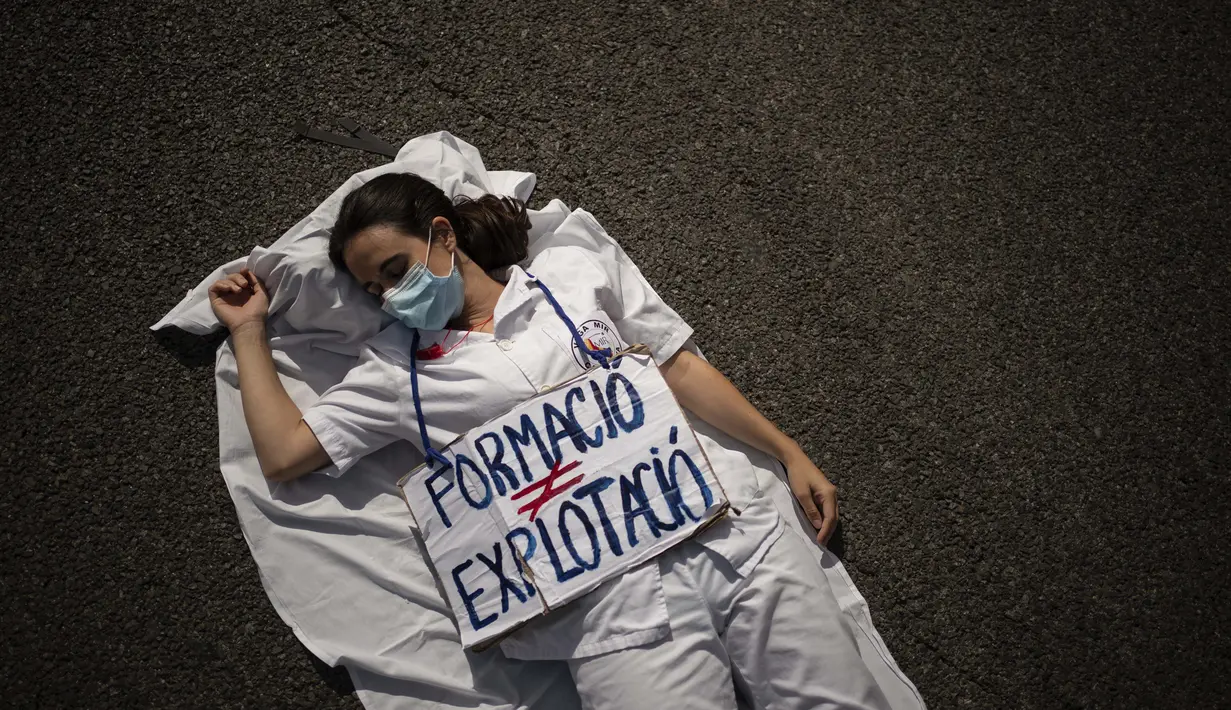 Seorang dokter residen berbaring di tengah jalan dengan spanduk bertuliskan dalam bahasa Inggris: "Pendidikan bukan eksploitasi", dalam demonstrasi menentang kondisi kerja mereka saat mogok di Barcelona, Spanyol pada 29 September 2020. (AP Photo / Felipe Dana)