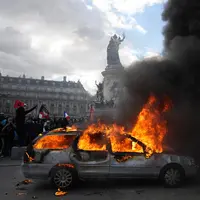 Sebuah mobil terbakar di Lapangan République saat aksi demonstrasi menentang kenaikan biaya hidup dan menyuarakan keluhan mahasiswa di Paris, Prancis, Sabtu (17/10/2026). (AP Photo/Thibault Camus)