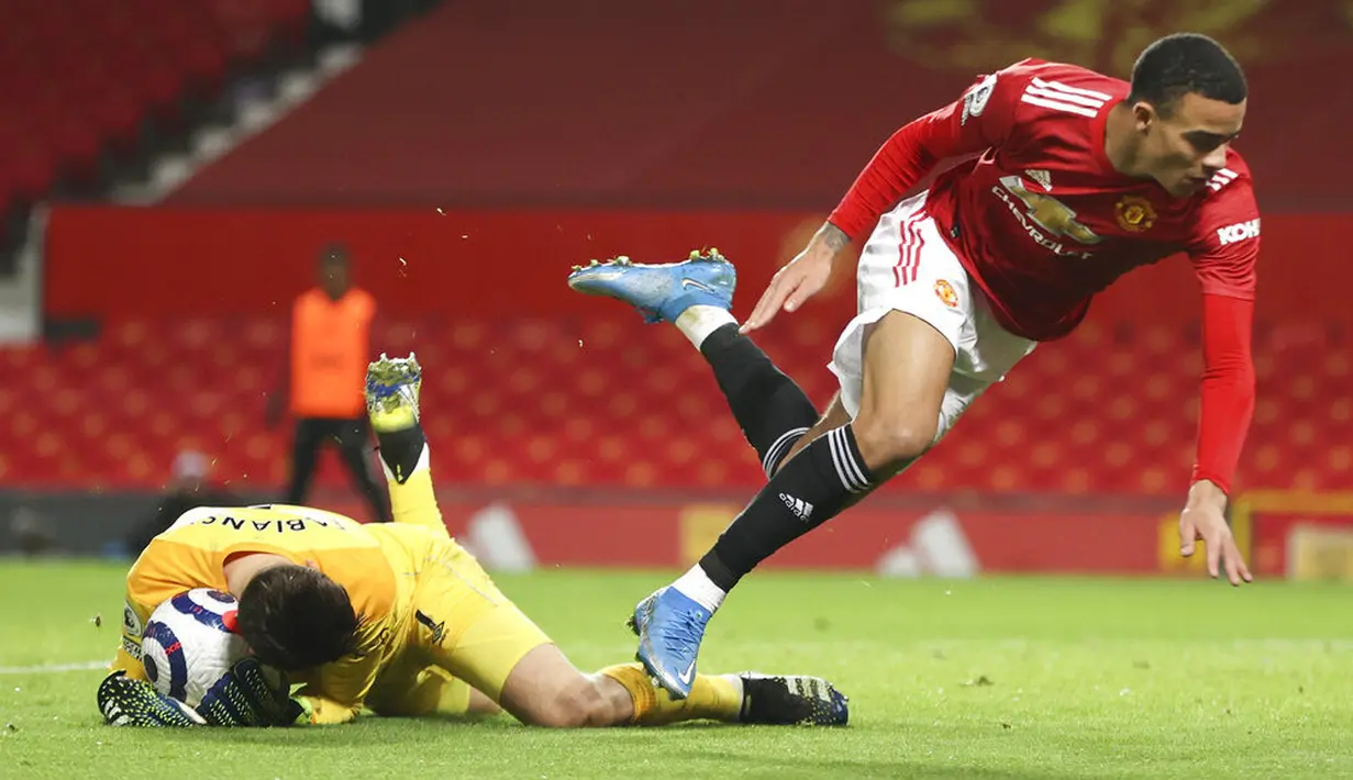 Penyerang Manchester United, Mason Greenwood, terjatuh saat berebut bola dengan kiper West Ham United, Lukasz Fabianski, pada laga Liga Inggris di Stadion Old Trafford, Minggu (15/3/2021). Setan Merah menang dengan skor 1-0. (AP/Clive Brunskill,Pool)