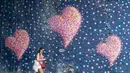 Seorang perempuan melewati lukisan mural lambang cinta di London, Inggris, pada 1 Agustus 2020. Pemerintah Inggris pada Jumat (31/7) mengumumkan penundaan pelonggaran beberapa langkah pembatasan menyusul jumlah infeksi virus corona yang meningkat. (Xinhua/Han Yan)