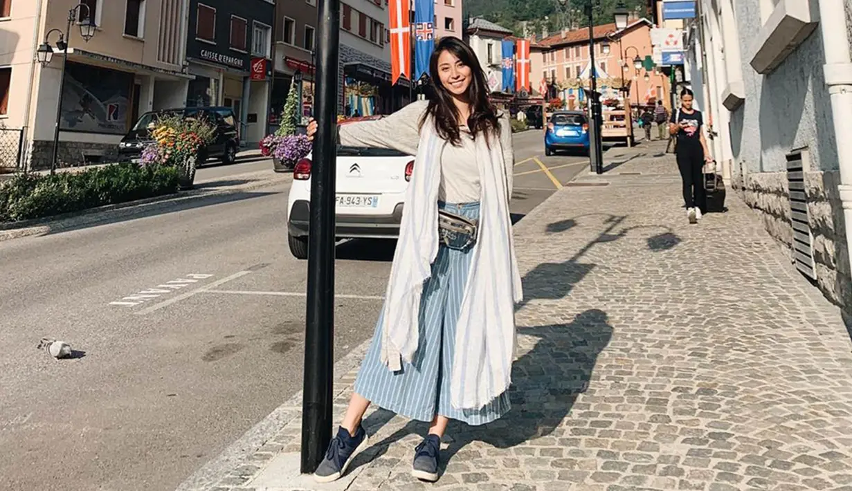 Berlibur ke Swiss, Clay tampil dengan cardigan putih bermotif garis biru dan celana kulot berwarna senada. (Liputan6.com/IG/@clairineclay)
