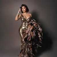 Rapper berbakat ini tampil memukau dalam gaun emas karya Roberto Cavalli yang menonjolkan siluet mermaid dengan korset yang mempertegas lekuk tubuhnya. [@iamcardib].