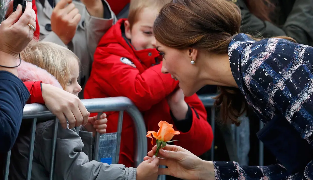 Kate Middleton menerima bunga yang diberikan oleh seorang gadis kecil setelah mengunjungi Meseum Nasional Sepak Bola di Manchester, Inggris (14/10). Kate tampil cantik didampingi suaminya Pangeran Wiliam. (Reuters/Phil Noble)