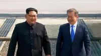 Pemimpin Korea Utara Kim Jong-un dan Presiden Korea Selatan Moon Jae-in berjalan melewati Zona Demiliterisasi, Jumat (27/4). Kim dan Moon menuju Rumah Perdamaian di wilayah Korsel untuk menggelar pertemuan tingkat tinggi (Korea Broadcasting System via AP)