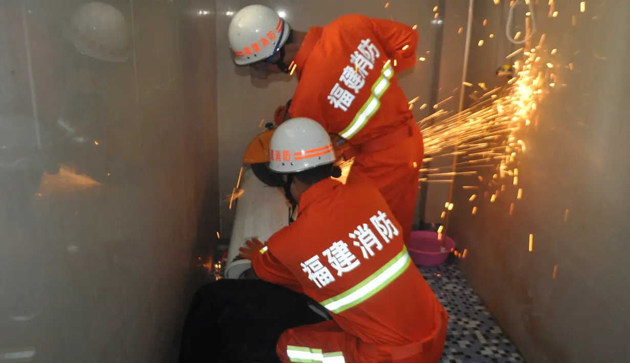 Petugas pemadam berusaha menolong seorang pria yang terjebak di dalam mesin cuci di Fuqing, China, 29 Mei 2016. Petugas memotong mesin cuci yang membuat kepala pria malang itu terjebak di dalamnya. (REUTERS/Stringer)