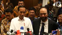 Presiden Joko Widodo atau Jokowi (kiri) didampingi Ketua Umum Partai Nasdem Surya Paloh (kanan) memberi keterangan saat menghadiri perayaan ulang tahun ke-8 Partai Nasdem di JIExpo, Jakarta, Senin (11/11/2019). Surya Paloh menyambut langsung kedatangan Jokowi di HUT Nasdem. (Liputan6.com/Angga Yunia