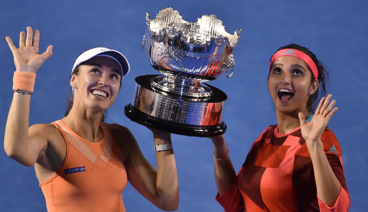 Martina Hingis (kiri) dan Sania Mirza berpose dengan trofi juara ganda putri setelah mengalahkan Lucie Hradecka dan Andrea Hlavackova di final tenis Australia Terbuka 2016 di Melbourne Park, Australia, (29/1/2016). (AFP/Peter Parks)