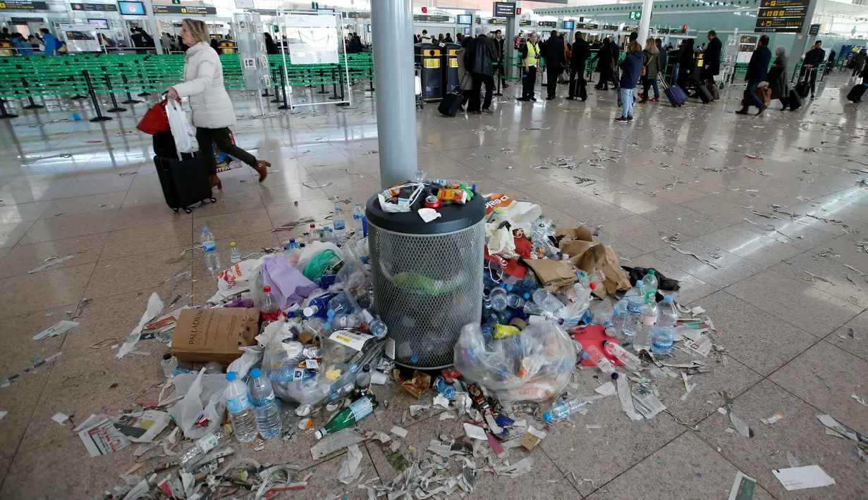Penumpang berjalan melewati sampah yang berserakan di Bandara Barcelona, Spanyol, Kamis (1/12). Sampah-sampah yang berserakan tersebut sebagai bentuk aksi protes para petugas kebersihan untuk pemotongan anggaran 1,3 juta Euro. (REUTERS/Albert Gea)