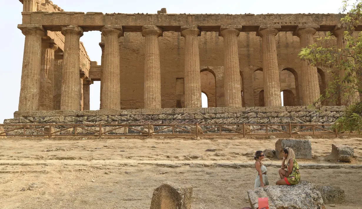 Turis saat mengunjungi Lembah Kuil selama gelombang panas di dekat Agrigento, Sisilia, Italia (11/8/2021). Gelombang panas yang berkelanjutan akan berlangsung hingga akhir pekan dengan suhu diperkirakan mencapai lebih dari 40 derajat Celcius di banyak bagian dari Italia. (AP Photo/Salvatore Cavalli)