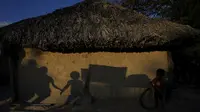Anak-anak bermain di depan rumah adat Kalunga quilombo, keturunan budak yang melarikan diri, di kawasan pedesaan Cavalcante di negara bagian Goias, Brasil, Senin (15/8/2022). (AP Photo/Eraldo Peres)