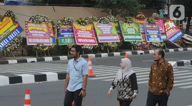 Pejalan kaki melintasi karangan bunga ucapan selamat yang berjejer di sekitar Gedung Merah Putih KPK, Jakarta, Jumat (20/12/2019). Papan karangan bunga tersebut berisi ucapan selamat terhadap dilantiknya pimpinan KPK periode 2019-2023. (merdeka.com/Imam Buhori)