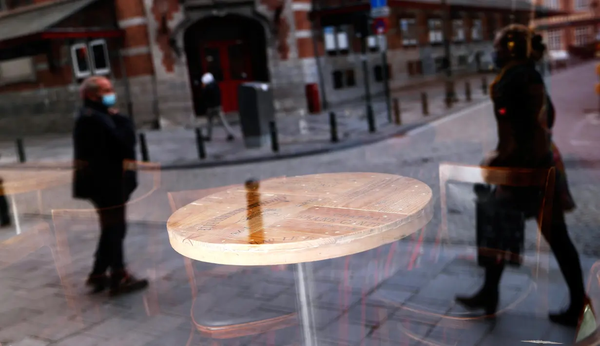 Refleksi orang-orang terlihat dari jendela depan sebuah bar yang tutup di pusat kota Brussel, Belgia, Kamis (8/10/2020). Brussels pada Rabu, 7 Oktober 2020, memutuskan menutup semua bar, ruang dansa, dan kafetaria selama sebulan sebagai upaya membendung lonjakan COVID-19. (AP Photo/Francisco Seco)