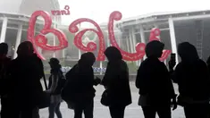 Warga berlindung dari hujan setibanya di Bandara Internasional Bali, Jumat (4/2/2022). Bali kembali dibuka untuk pelancong asing dari semua negara setelah penerbangan internasional dilanjutkan untuk pertama kalinya dalam dua tahun, tapi pengunjung tetap wajib karantina. (AP Photo/Firdia Lisnawati)