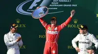 Pembalap Ferrari, Sebastian Vettel berpose dengan trofinya setelah memenangi balapan GP Australia di Sirkuit Albert Park, Melbourne, Minggu (26/3). Pembalap asal Jerman tersebut sukses mengalahkan pesaing terberatnya Lewis Hamilton. (WILLIAM WEST/AFP)