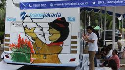Sejumlah anak berkebutuhan khusus melukis bus Transjakarta di halaman Balai Kota, Jakarta, Jumat (20/4). Kegiatan tersebut dalam rangka memperingati Hari Kartini. Tema lukisan yang diangkat adalah ‘Ibuku Perempuan Tangguh’. (Liputan6.com/Arya Manggala)