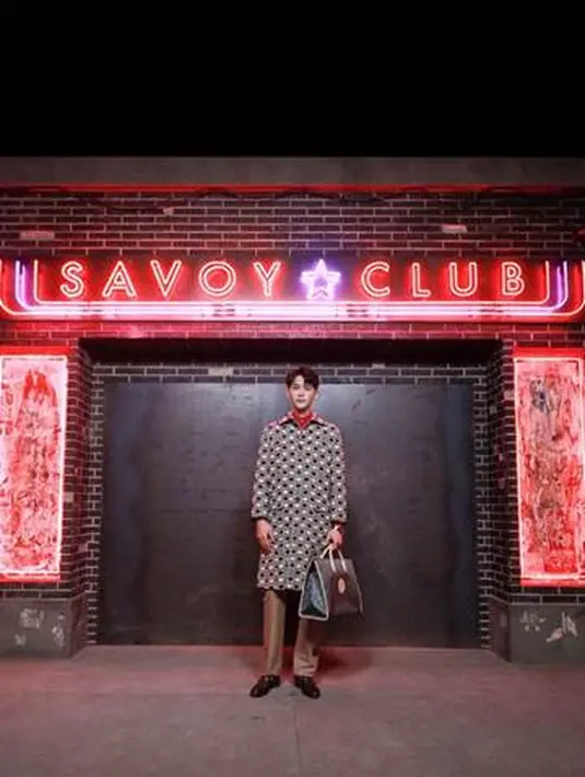 Tang Xiaotian mengenakan mantel katun dan linen Gucci Ouverture berwarna biru dan beige. Motif all-over GG Fancy yang mendominasi dipadukan dengan kemeja sable merah. Camel pants dengan detail Gucci Eschatology dan sepatu kulit cokelat memberikan perpaduan menarik pada keseluruhan outfit (Gucci)