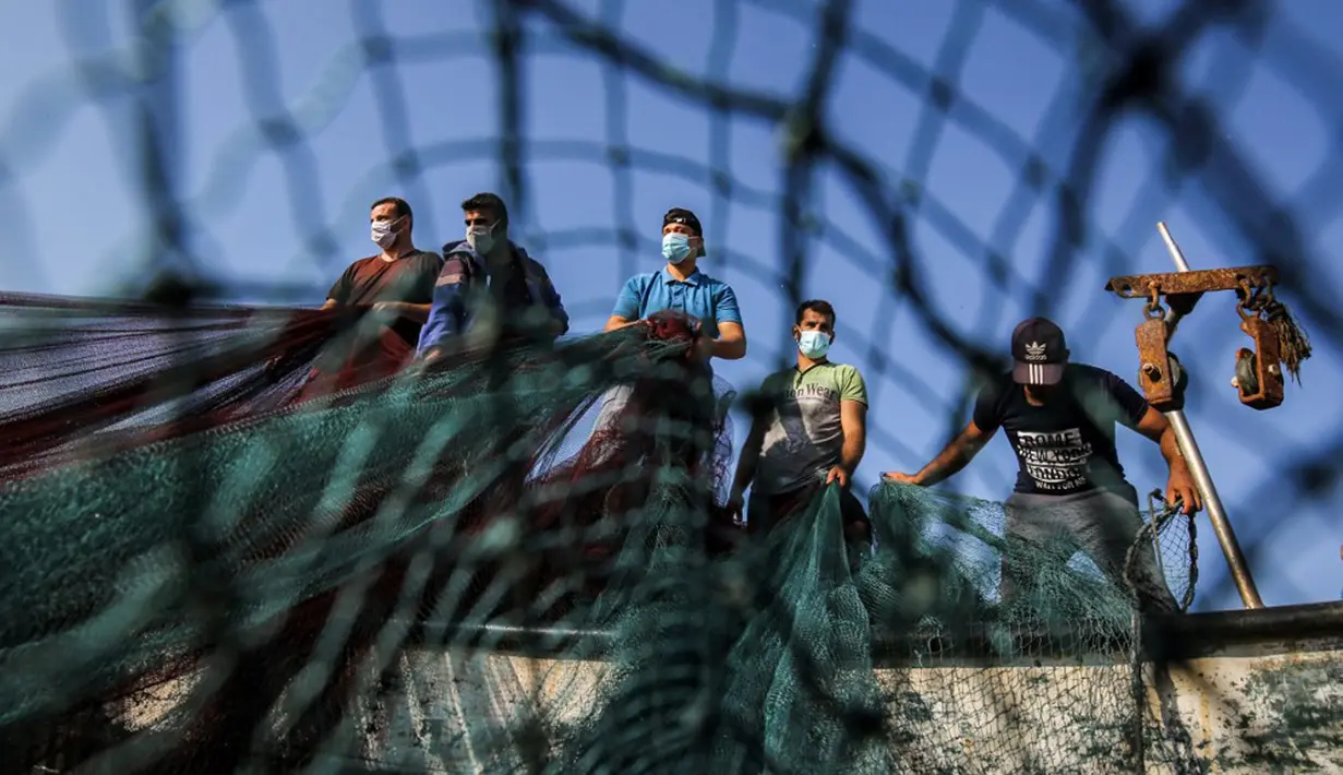 Nelayan Palestina yang mengenakan masker karena pandemi virus corona COVID-19 menyiapkan jala ikan di sepanjang pantai Laut Mediterania, Rafah, Jalur Gaza, Rabu (2/9/2020). (SAID KHATIB/AFP)