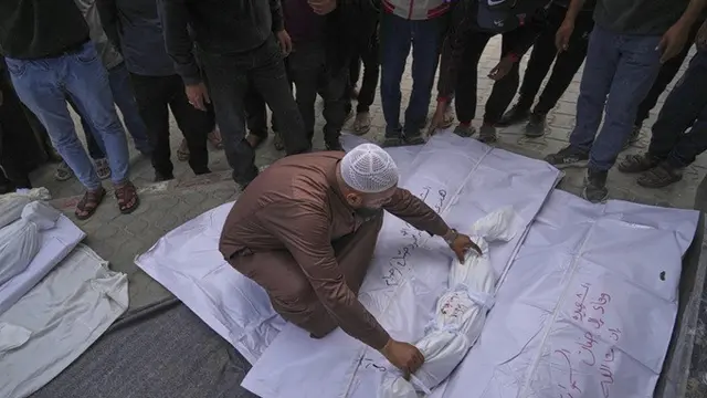 Seorang petugas kamar mayat meletakkan jenazah seorang anak di luar Rumah Sakit Al-Shifa, Kota Gaza, di antara jenazah korban lainnya yang tewas dalam setidaknya dua serangan terpisah oleh Israel, Senin (5/5/2025).