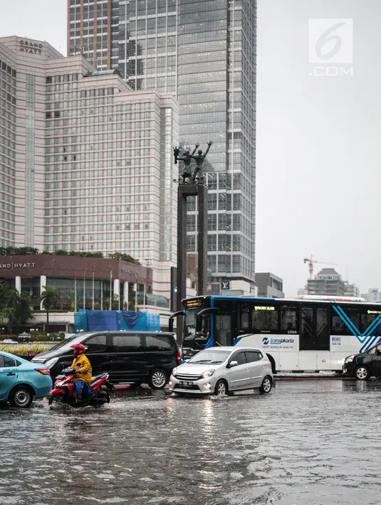 Sejumlah kendaraan melintas menerjang genangan air di kawasan Bunderan HI, Jakarta, Kamis (22/11). Genangan air hujan setinggi 40 cm tersebut disebabkan hujan deras yang melanda Jakarta pada siang hari. (Liputan6.com/Faizal Fanani)