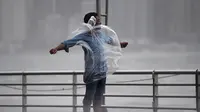 Seorang pria berdiri melawan angin kencang dan hujan yang ditimbulkan oleh Topan Hato di Hong Kong (23/8). Terjangan topan Hato mengakibatkan lebih dari 400 penerbangan dibatalkan. (AFP/Anthony Wallace)