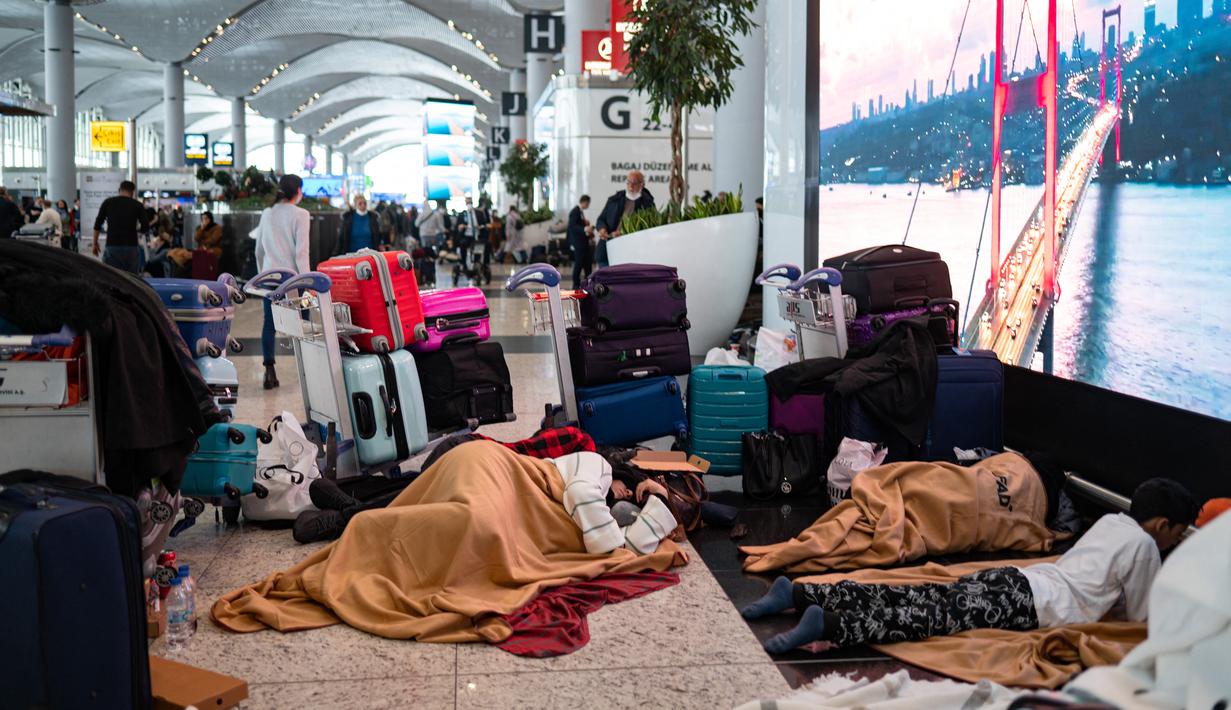 Penumpang yang terdampar menunggu di bandara Istanbul, di mana penerbangan dibatalkan karena badai salju dan hujan salju lebat, di Istanbul, Turki, pada 25 Januari 2022. Penutupan salah satu bandara tersibuk di Eropa ini akibat hantaman badai salju yang menghambat operasional. (Yasin AKGUL/AFP)