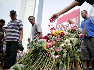 Pengunjung car free day menaburkan bunga di atas papan bertuliskan "Terima Kasih Pejuang Demokrasi" di Bundaran HI, Jakarta, Minggu (28/4/2019). Kegiatan tabur bunga tesebut sebagai bentuk belasungkawa atas meninggalnya petugas KPPS dalam Pemilu 2019. (Liputan6.com/Faizal Fanani)