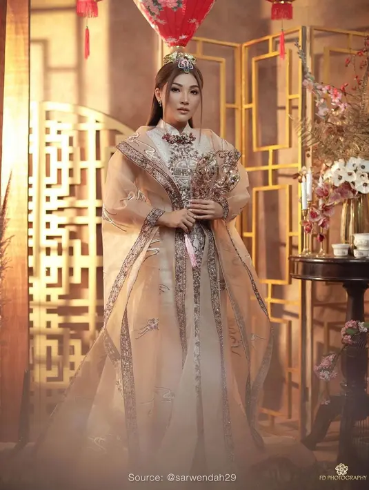 Sarwendah terlihat bak putri kerajaan Cina dengan ceongsam luar biasa bernuansa cokelat keemasan. Cheongsam ini memiliki outer transparan dengan bordir yang serasi Belum lagi tatanan dan aksesori rambut yang dikenakan Sarwendah di sini, menambah nuansa megah nan mewah pada penampilannya secara keseluruhan. Foto: Instagram.