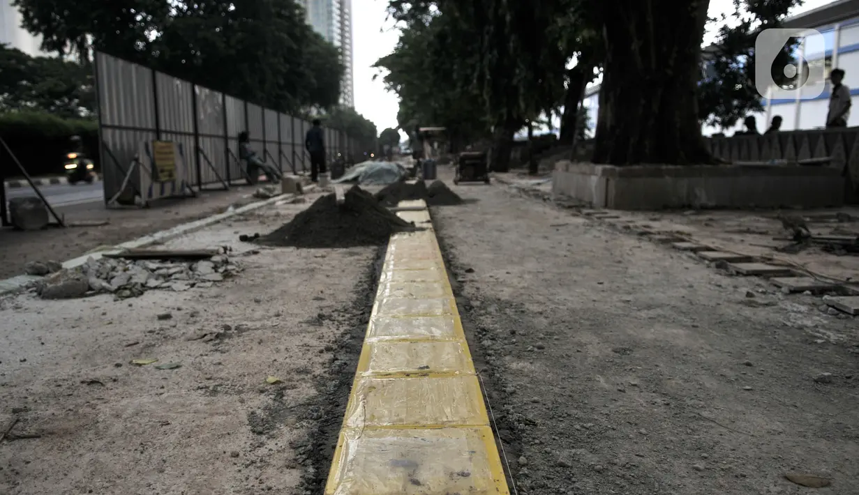 Pekerja Dinas SDA menyelesaikan proyek revitalisasi trotoar di Jalan RM Margono Djojohadikoesoemo, Jakarta, Kamis (16/1/2020). Trotoar di sisi selatan Kanal Banjir Barat itu akan dilengkapi taman dan deck view untuk melihat pemandangan Kali Ciliwung dan gedung perkantoran (merdeka.com/Iqbal Nugroho)