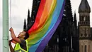 Seorang pria mengibarkan bendera warna pelangi usai pengumuman legalisasi undang-undang pernikahan sesama jenis di Cologne, Jerman (30/6). (AFP PHOTO / DPA / Oliver Berg / Germany OUT)
