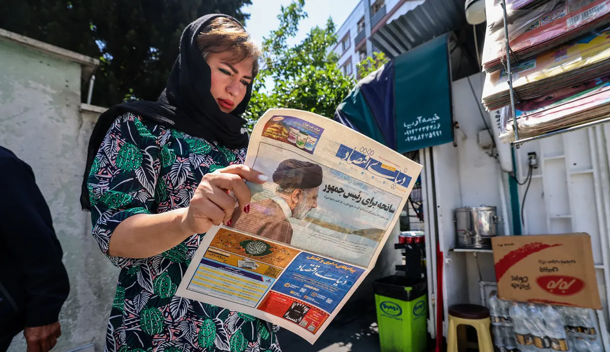 Seorang perempuan membaca surat kabar dengan laporan halaman depan tentang jatuhnya helikopter presiden Iran Ebrahim Raisi di luar kios di Teheran, Senin (20/5/2024). (Atta KENARE / AFP)