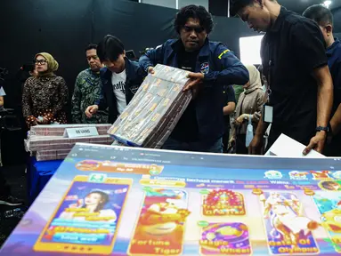 Petugas merapikan barang bukti usai sejumlah Menteri Kabinet Merah Putih memberikan keterangan terkait capaian desk pemberantasan perjudian daring dan desk keamanan siber dan perlindungan data di Kantor Kementerian Komunikasi dan Digital (Komdigi), Jakarta, Kamis (21/11/2024). (Liputan6.com/Angga Yuniar)