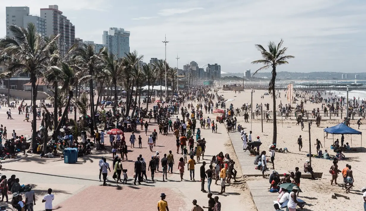 Ribuan wisatawan bersuka ria saat perayaan Tahun Baru di North Beach, Durban, Afrika Selatan, 1 Januari 2022. Pemerintah Afrika Selatan mencabut pembatasan COVID-19 dengan menghapus jam malam dari tengah malam hingga pukul 04.00. (Rajesh JANTILAL/AFP)