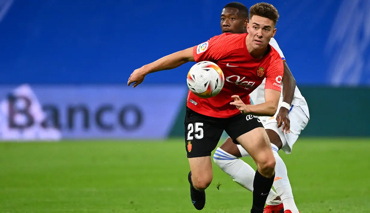 Pemain depan Mallorca, Matthew Hoppe (depan) bersaing dengan bek Real Madrid, David Alaba pada jornada keenam La Liga Spanyol di Santiago Bernabeu, Kamis (23/9/2021) dini hari WIB. Real Madrid berpesta gol usai melibas Real Mallorca 6-1. (GABRIEL BOUYS / AFP)