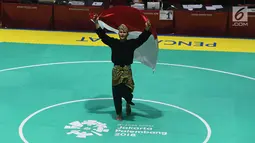 Pesilat Indonesia Sugianto membawa bendera merah putih usai meraih medali emas dalam babak final tunggal putra pencak silat seni Asian Games 2018 di Padepokan Pencak Silat Taman Mini Indonesia Indah (TMII), Jakarta, Rabu (29/8). (Merdeka.com/ Imam Buhori)