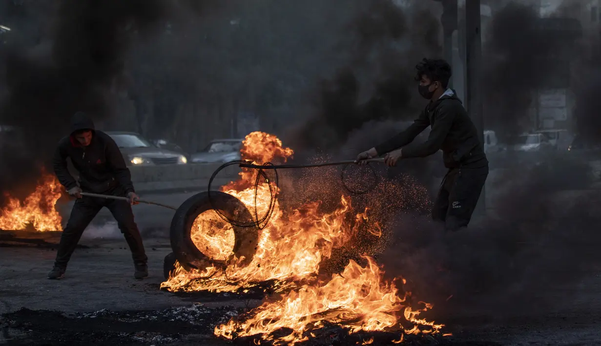 Pengunjuk rasa anti-pemerintah membakar ban untuk memblokir jalan, selama protes di Beirut, Lebanon, Selasa (2/3/2021). Warga Lebanon yang marah memblokir jalan di seluruh negeri dengan membakar ban dan tempat sampah setelah mata uang Lebanon jatuh ke titik terendah baru. (AP Photo/Hassan Ammar)