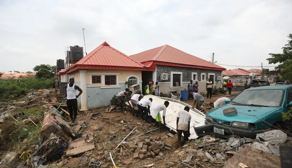 Orang-orang berusaha untuk menarik gerbang yang ditarik oleh air banjir di jalan yang terkena banjir bandang setelah hujan deras di Trademoore Estate, Lugbe, Abuja, Nigeria (13/9/2021). (AFP/Kola Sulaimon)