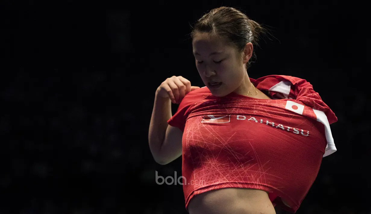 Karena terbiasa, Nozomi Okuhara, sudah tidak kesulitan ganti baju di pinggir lapangan. (Bola.com/Vitalis Yogi Trisna)
