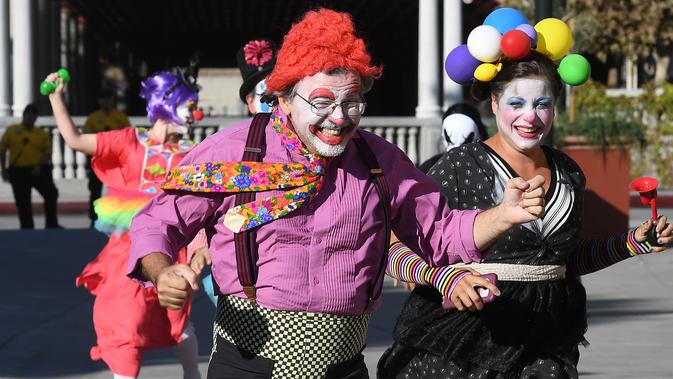 Para peserta berkostum badut berlarian selama acara 'Running of the Clowns' di Pasadena, California pada 21 Oktober 2018. Lari dikejar kawanan badut ini merupakan parodi yang mengolok-olok lomba dikejar banteng di Pamplona, Spanyol. (Mark RALSTON/AFP)