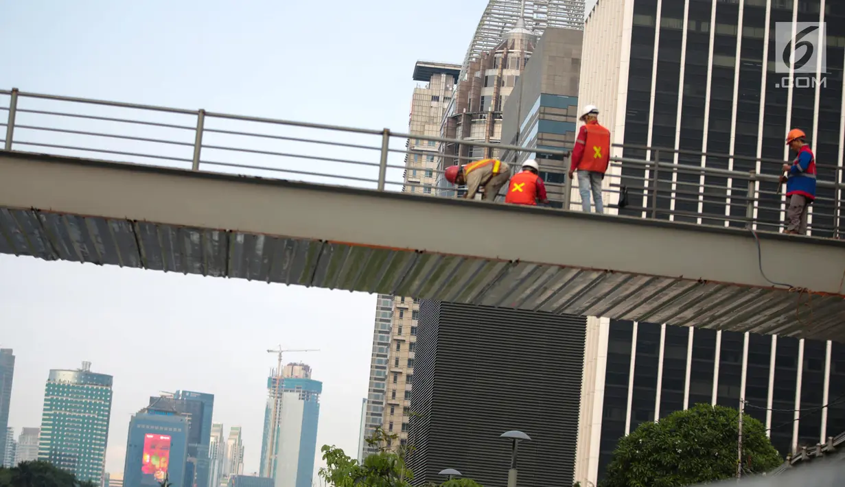 Pekerja menyelesaikan revitalisasi Jembatan Penyeberangan Orang (JPO) Gelora Bung Karno (GBK), Jakarta, Selasa (27/11). Pembangunan tiga JPO Polda Metro Jaya, GBK dan Bundaran Senayan menelan Rp56 miliar. (Liputan6.com/Faizal Fanani)