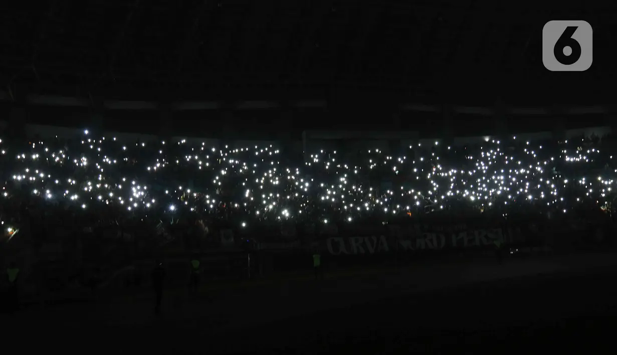 Para suporter berusaha menyalahkan flash dari ponsel masing-masing untuk membantu penerangan di stadion tersebut. (Liputan6.com/Herman Zakharia)