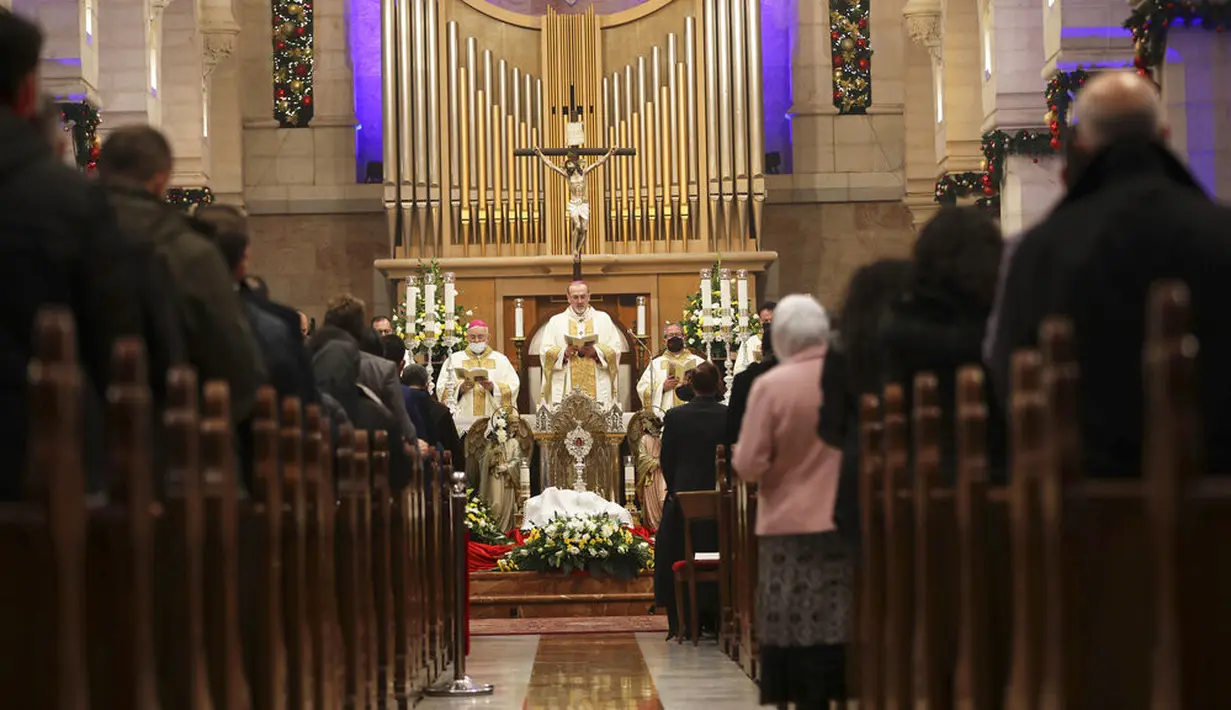 Administrator Apostolik Gereja Latin di Tanah Suci Pierbattista Pizzaballa (tengah) memimpin misa pada malam Natal di Gereja Kelahiran, Betlehem, Tepi Barat, Jumat (25/12/2020). Natal tahun ini dirayakan oleh umat Kristiani dunia di tengah pandemi COVID-19. (Abed Al Hashlamoun/Pool Photo via AP)