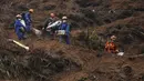 Pekerja darurat yang membawa barang-barang yang dibungkus tas turun dari lereng bukit setelah melakukan operasi pencarian di dekat lokasi kecelakaan pesawat Boeing 737-800 milik China Eastern Airlines di desa Molang, di provinsi Guangxi, China barat daya, Rabu (24/3/2022). (AP Photo/Ng Han Guan)