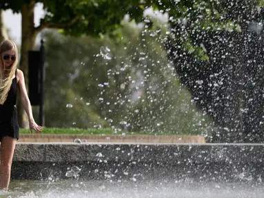 Seorang gadis mendinginkan kakinya di air mancur sebuah taman di dekat Kuil Debod di Madrid saat terjadi gelombang panas, Spanyol pada 13 Juli 2017. (AFP Photo/Javier Soriano)