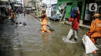 Petugas PPSU membersihkan sampah saat terjadi banjir rob di Pelabuhan Kali Adem, Muara Angke, Jakarta, Selasa (9/11/2021). Walau terendam banjir rob, petugas PPSU tetap sigap bersihkan sampah yang mengambang terbawa air laut. (Liputan6.com/Faizal Fanani)