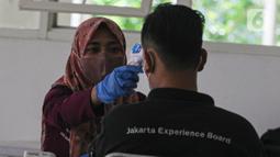 Petugas kesehatan mengecek suhu tubuh tenaga kesehatan relawan yang bertugas di RSDC, Wisma Atlit, Kemayoran, Jakarta. Rabu (3/8/2022). Pemberian vaksinasi Covid-19 dosis booster ke-2 tersebut diberikan dengan interval 6 bulan sejak vaksinasi dosis booster pertama. (Liputan6.com/Faizal Fanani)