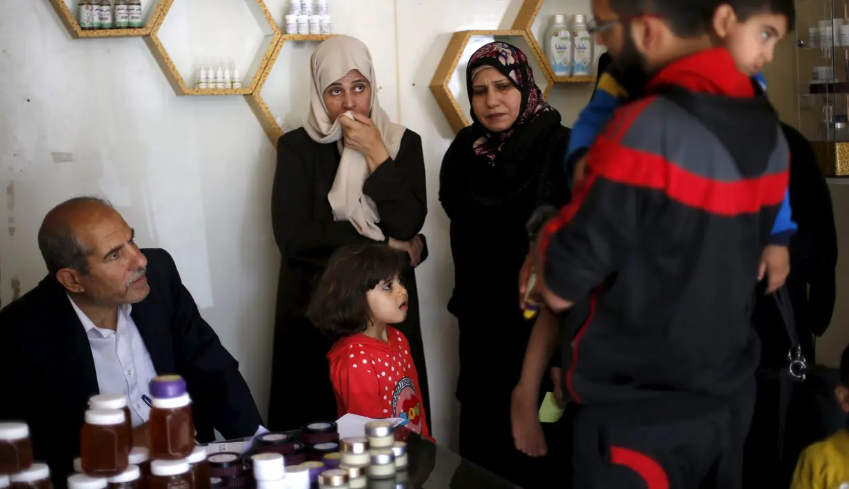 Rateb Samour (kiri) berbincang dengan pasiennya di klinik miliknya di Kota Gaza, 11 April 2016. Samour yang merupakan insinyur pertanian Palestina itu mewarisi keterampilan terapi sengatan lebah dari ayahnya (REUTERS/Suhaib Salem)