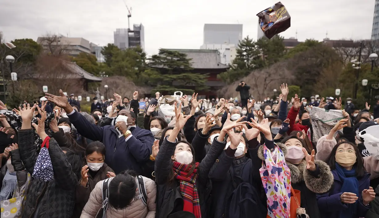 Orang-orang mencoba menangkap kacang keberuntungan yang disebarkan selama "Mame-maki", upacara melempar kacang, di kuil Buddha Zojoji, Tokyo, Jumat (3/2/2023). Pada tradisi ini seseorang akan berperan sebagai setan, sementara orang-orang lain akan melemparinya dengan kacang kedelai sambil merapal, "Nasib baik masuklah, roh jahat keluarlah". (AP Photo/Eugene Hoshiko)