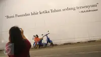 Seorang anak kecil berpose di depan mural bertema Kota Bandung di Jalan Asia Afrika, Bandung, Jawa Barat, Selasa (5/7). Dua buah mural tersebut menjadi lokasi favorit bagi warga dan wisatawan di Bandung untuk berfoto. (Liputan6.com/Immanuel Antonius)